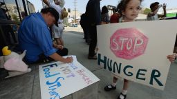 A girl  joins her father and other activists in June in Los Angeles protesting a farm bill that would cut funding for SNAP, or the food stamp program.
