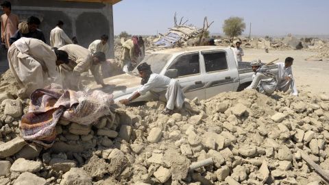 People clear debris off of a truck in Awaran on September 25.