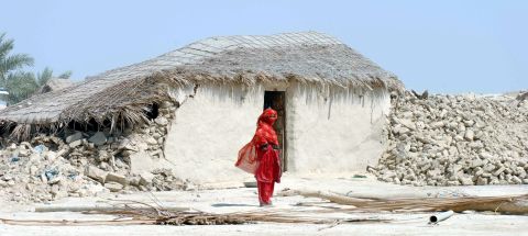A woman stands in front of the rubble of her destroyed home in Balochistan province on September 25.