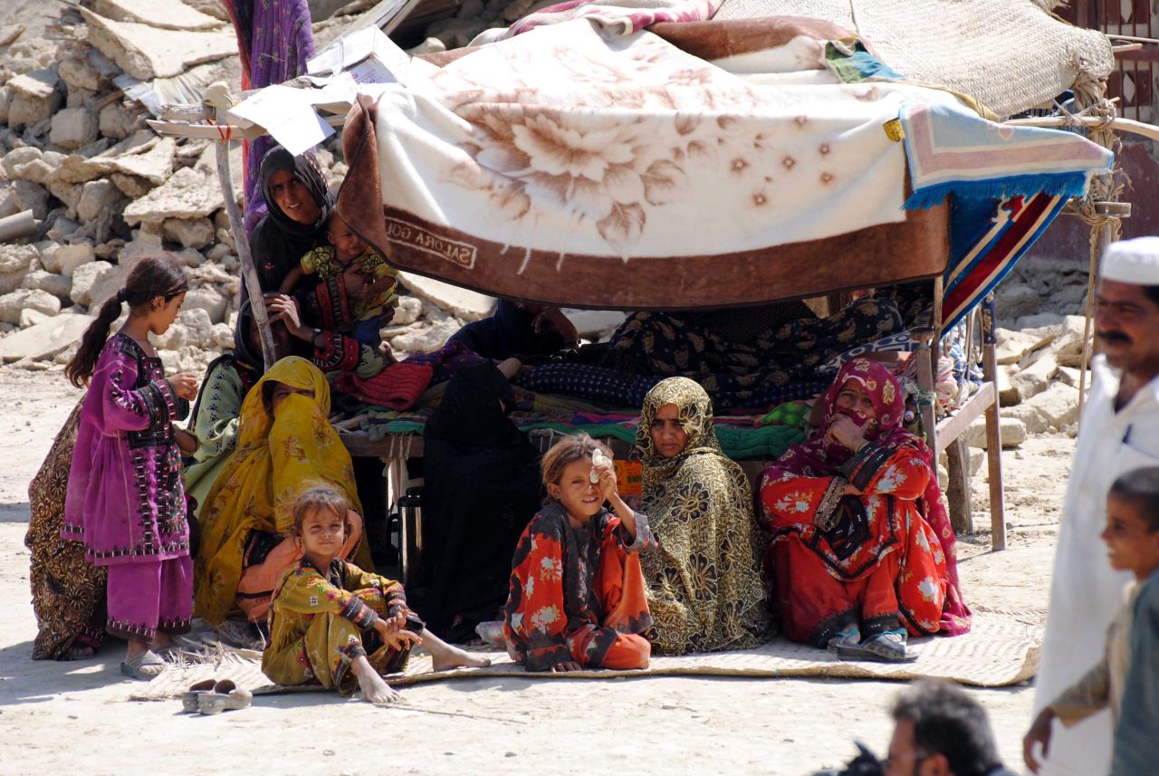 People sit under a makeshift sunroof near the rubble of their destroyed homes on September 25.