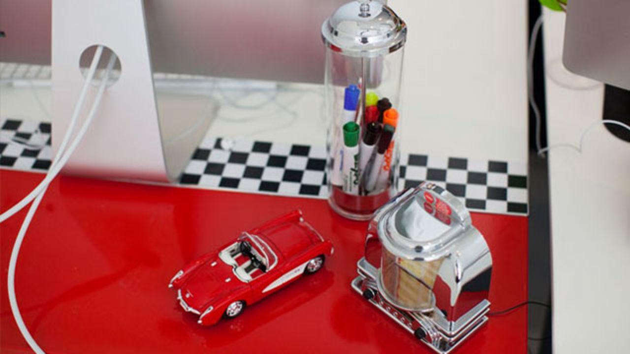 Brit + Co. sponsored a "Pimp My Desk" contest for its employees. Winner Dzuy Linh created a diner-themed desk using 1950s-themed objcts as accessories and vinyl decals to create a red and checkerboard base. 