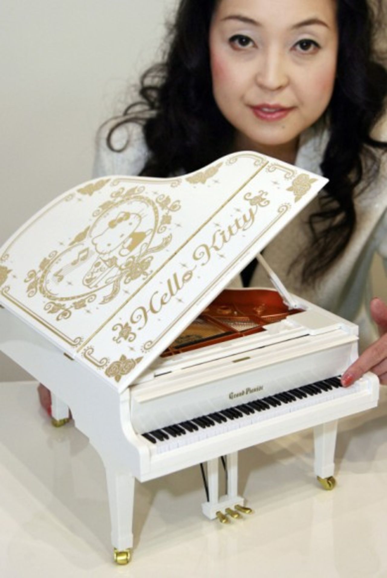 Una empleada de la empresa japonesa Sega muestra el piano de cola más pequeño del mundo versión Hello Kitty, que cuenta con 88 teclas que funcionan y puede tocar automáticamente 115 canciones ya instaladas.