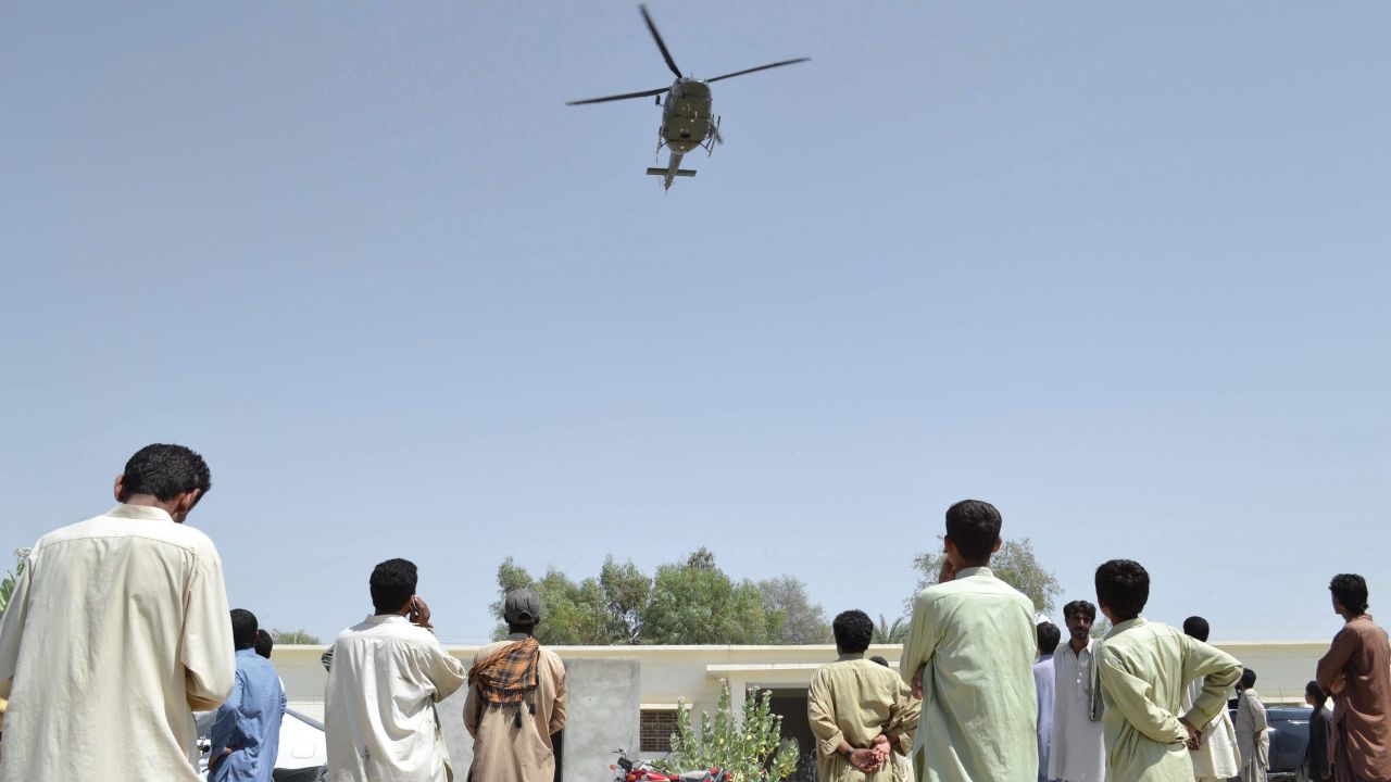 A Pakistani Army helicopter hovers over people as they wait for relief in Awaran on September 26.