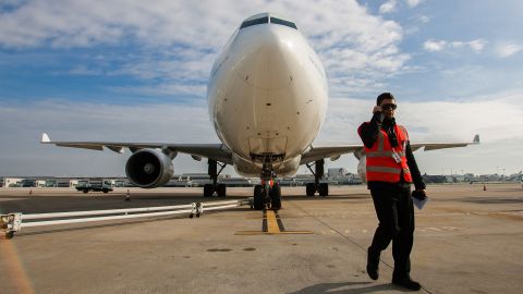 An airport worker speaks on a radio beside a TAP SGPS SA Airbus A330-223 airliner at Lisbon International (Portela) airport, operated by ANA-Aeroportos de Portugal SA, in Lisbon, Portugal, on Tuesday, Jan. 8, 2013. Portugal's government agreed to sell state-owned airport operator ANA-Aeroportos de Portugal SA to Vinci SA for 3.08 billion euros ($4.07 billion), raising money for the debt-strapped country. Photographer: Mario Proenca/Bloomberg via Getty Images