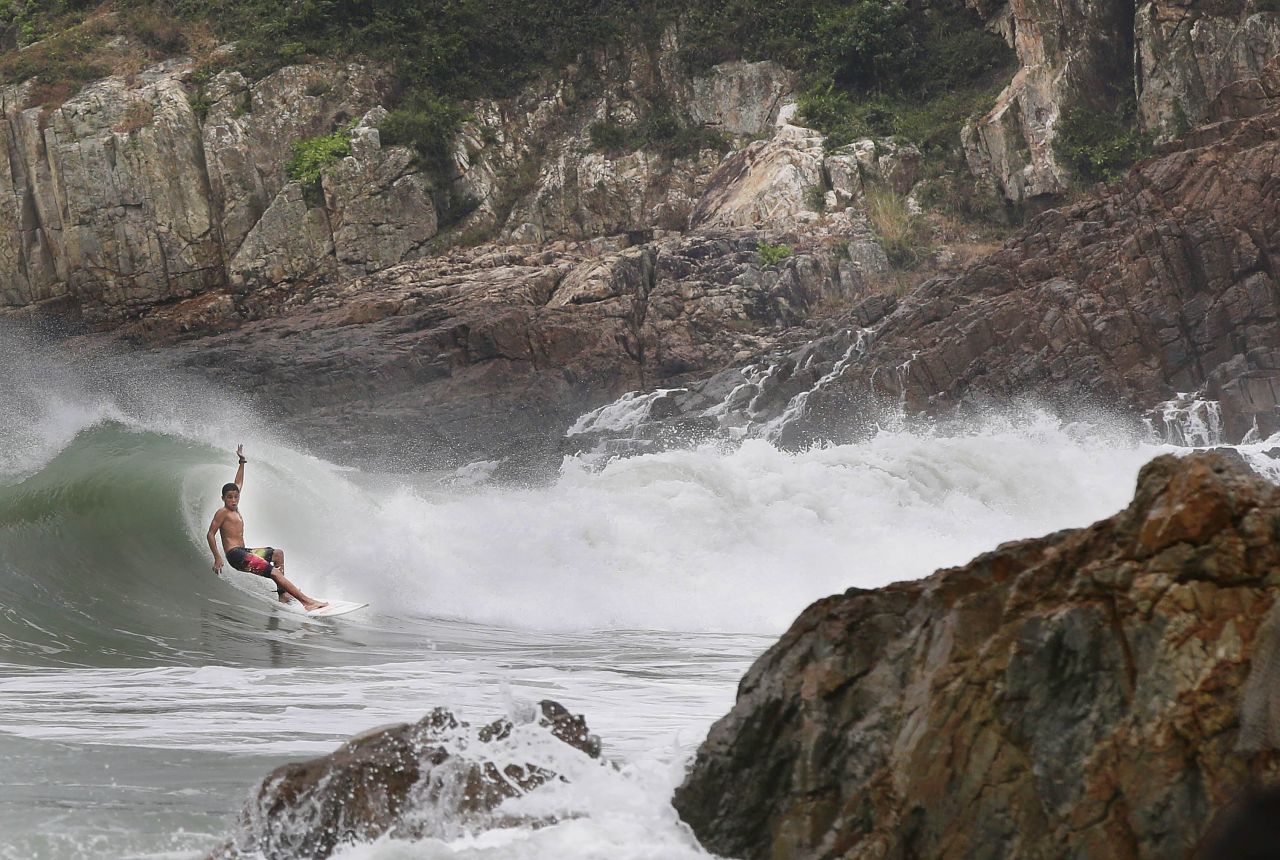 A surfer catches a wave by the rocks at Big Wave Bay on September 22, in Hong Kong, as Typhoon Usagi approaches the island.