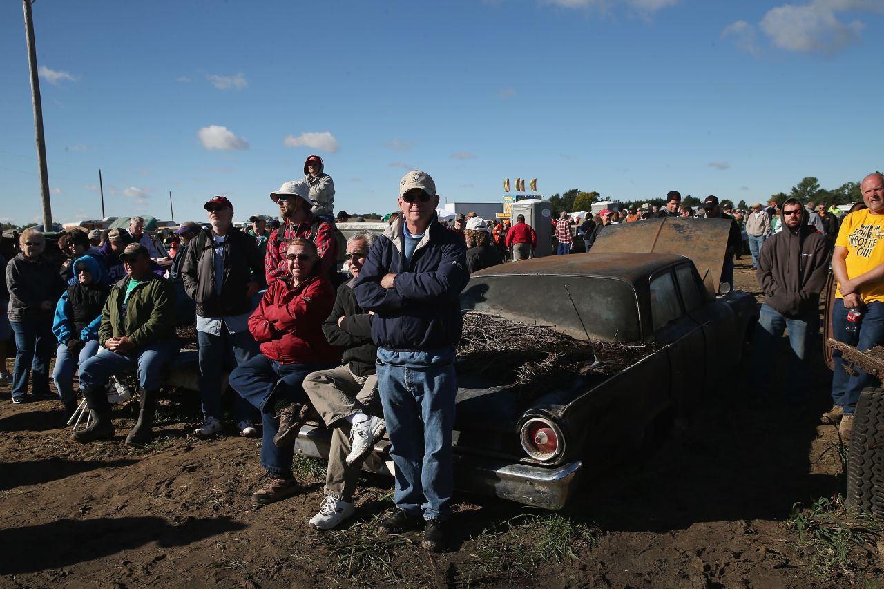 Men sit on the hood of an old car during the auction on Saturday.