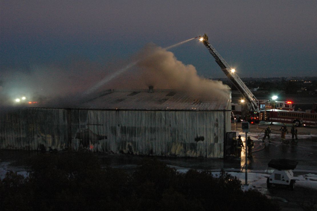 Firefighters pour water on a hangar after a plane crashed into it Sunday night in Santa Monica, California.