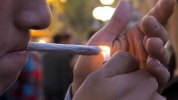 A young man lights a marijuana cigarette in Uruguay.