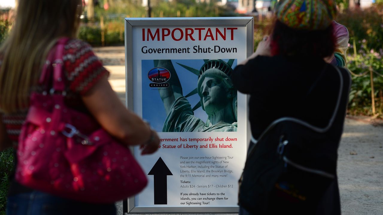 People look at a sign announcing that the Statue of Liberty is closed in New York on October 1.