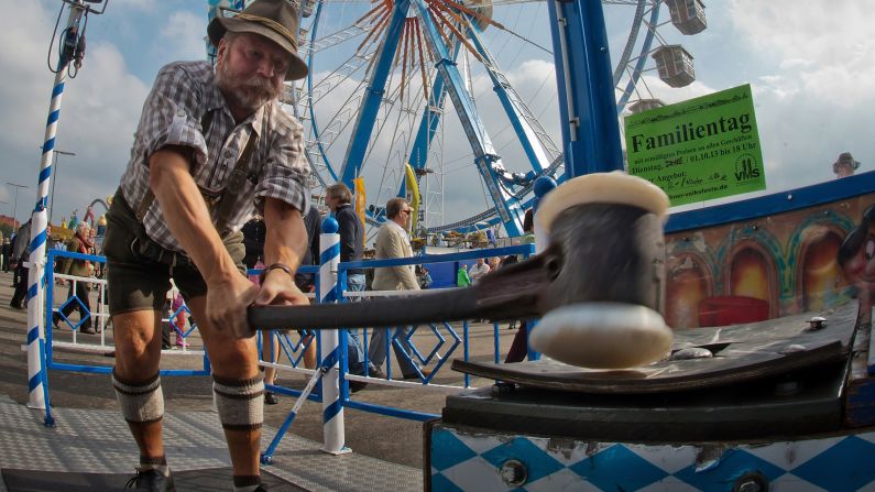 A man swings a hammer down on a "strong man" game at the festival on Tuesday, October 1.