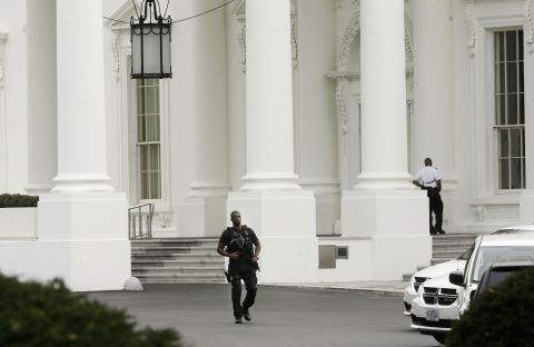 A member of the Secret Service counterassault team walks past the entrance of the White House.
