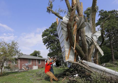 Residents try to free a house panel from where it was lodged against a tree following a tornado in Bennet, Nebraska, Friday, October 4. Powerful storms struck the Midwest on Friday, dumping heavy snow in South Dakota, spawning a tornado in Nebraska and threatening dangerous thunderstorms from Oklahoma to Wisconsin. 