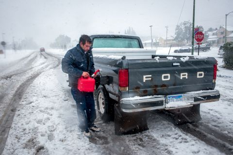 Ronnie Tonuci, 21, puts gas in his truck after it ran out in the middle of an early season blizzard on October 4, in Rapid City, South Dakota. 