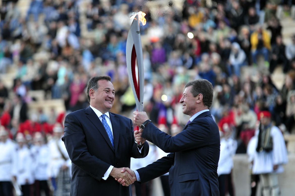 Kapralos (left) hands the flame over to Russia's Deputy Prime Minister Dmitry Kozak ahead of its trip to Moscow, before starting its 65,000-kilometer journey in Sochi on October 7.