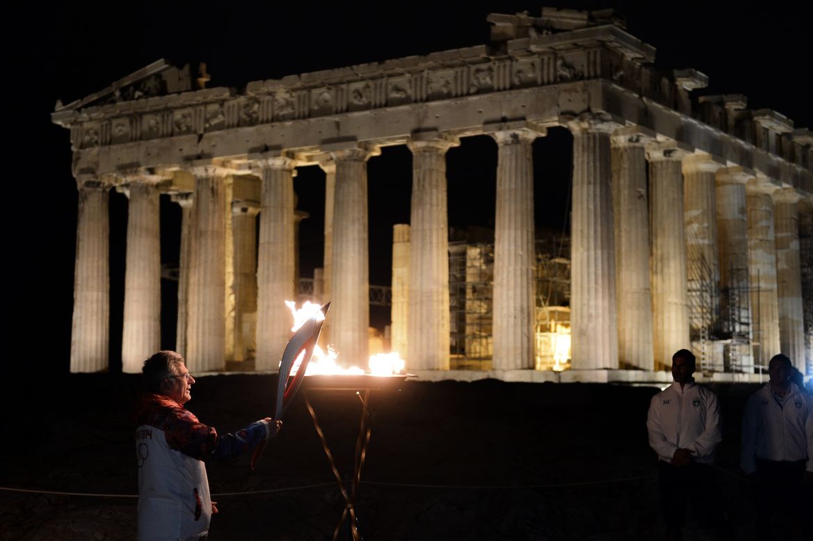 A previous torchbearer, Manolis Katsiadakis the general secretary of Greece's Olympic Committee, lights the flame in front of the ancient Temple of Parthenon on top of the Acropolis hill on October 4. 