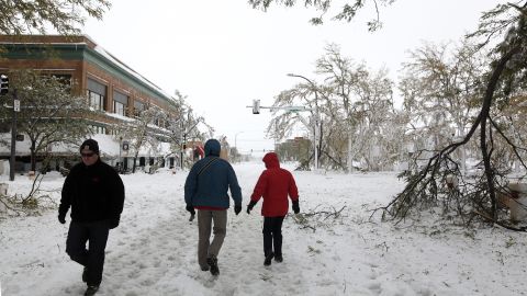 People walk down snow-covered streets in downtown Rapid City, South Dakota, on October 5. 