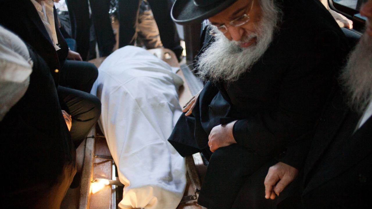 Orthodox Jews sit next to the rabbi's body on October 7 in Jerusalem.