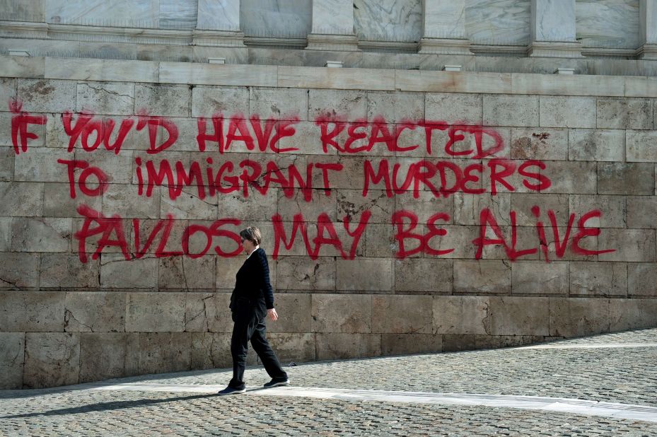 A woman walks past graffiti sprayed on the Athens Academy building in reference to the murder of anti-fascist musician Pavlos Fyssas on October 4, 2013, allegedly by a Golden Dawn sympathizer. The killing prompted a crackdown on the party.