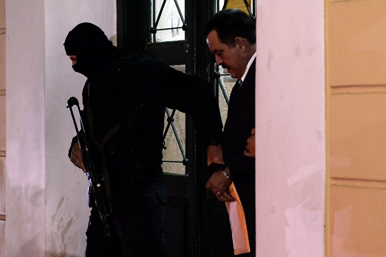 Pappas is escorted by a policeman after a hearing at the Athens court on October 3, 2013.