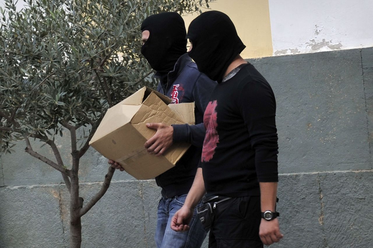 Anti-terror police bring a box containing the case file against an arrested extreme far-right Golden Dawn party member to an Athens court on October 2, 2013. 