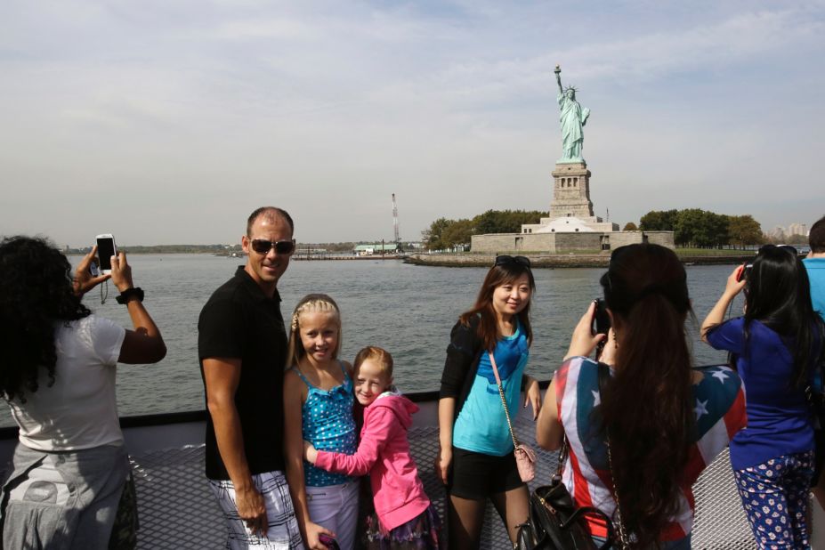 Tourists take photos of the Statue of Liberty while riding a tour boat in New York Harbor on October 3. The statue is adminstered by the National Park Service and is closed as a result of the government shutdown.