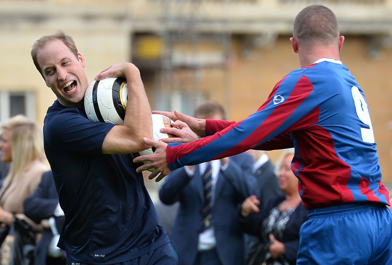 Prince William is clearly enjoying himself as he wrestles to keep the ball during a training session at Buckingham Palace. 