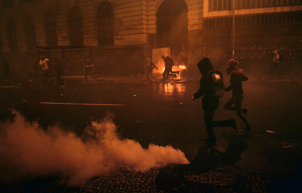 Demonstrators run after riot police used tear gas to disperse the crowds during the October 7 Rio protests.