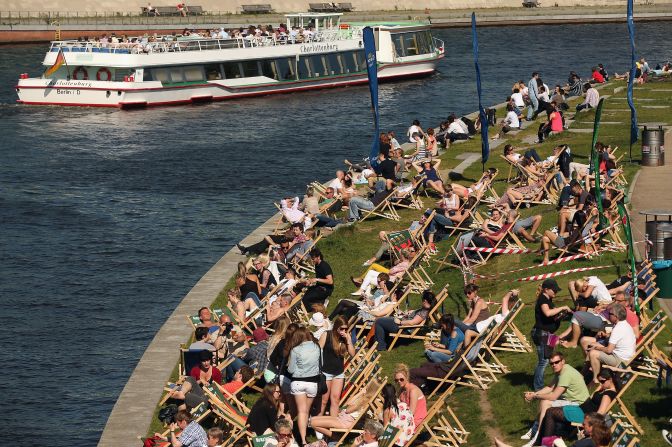 People enjoy an outdoor bar along the banks of the River Spree in Berlin.  Areas on both sides of the river have been transformed into bars and community gardens, artists' studios and underground nightclubs where residents and tourists  can gather. 