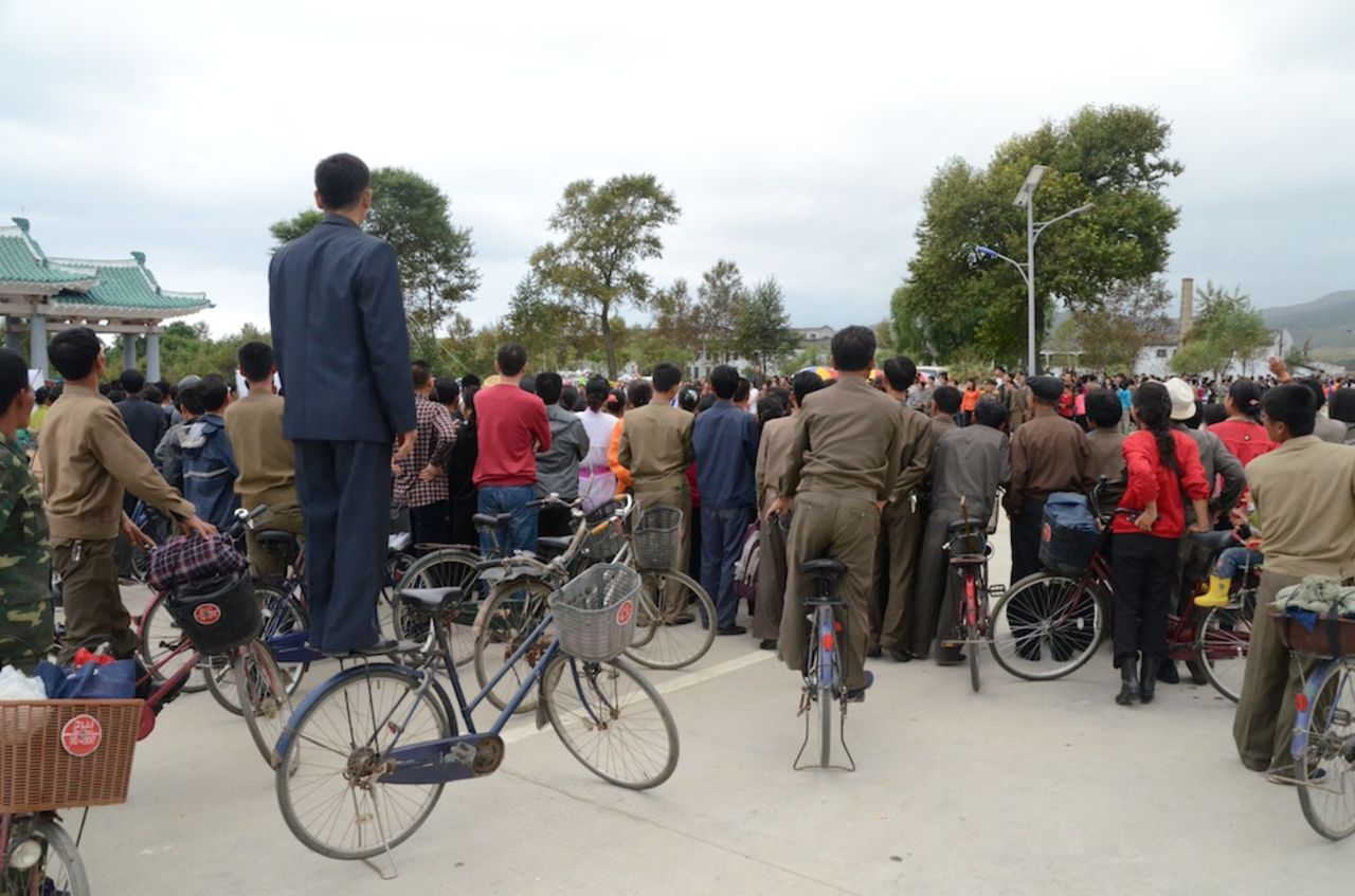 Huge crowds -- some of whom standing on their own bikes -- as they await cyclists by the race finish line in Rason.