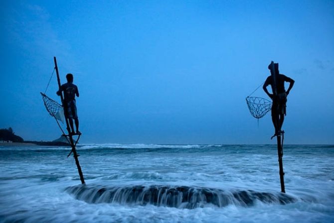 At dawn, fishermen Sunil Nishanti (left) and Anil Madushanka sit on wooden stilts they both inherited from their fathers. Sunil and his family lost almost everything when the tsunami of 2004 flooded the bay where they lived on the coast of Ahangama, Sri Lanka. For now, he still earns his living from fishing but his catch is barely enough to feed his own family. 