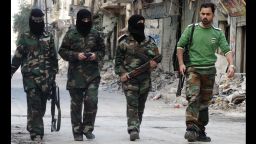 Masked female rebel fighters walk alongside their trainer on a street in the Salaheddin district of Aleppo on October 8.