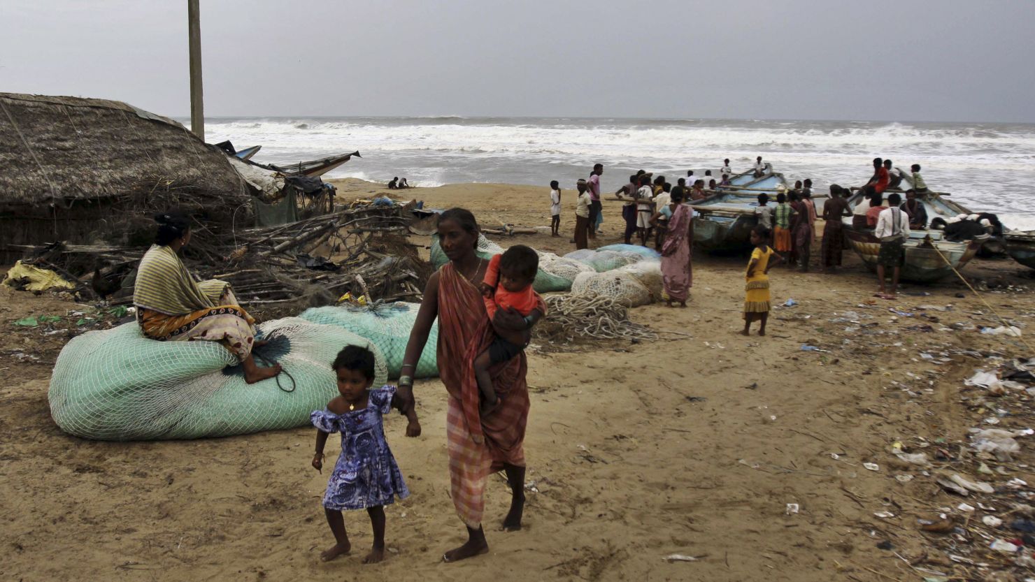 An Indian woman leaves the coast with her children as other villagers look at the Bay of Bengal, India, on Friday.