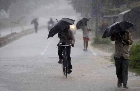 Villagers walking to the cyclone shelter try to block the heavy wind and rain with umbrellas near Chatrapur on October 12.