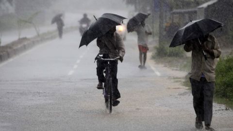 Villagers walking to the cyclone shelter try to block the heavy wind and rain with umbrellas near Chatrapur on October 12.