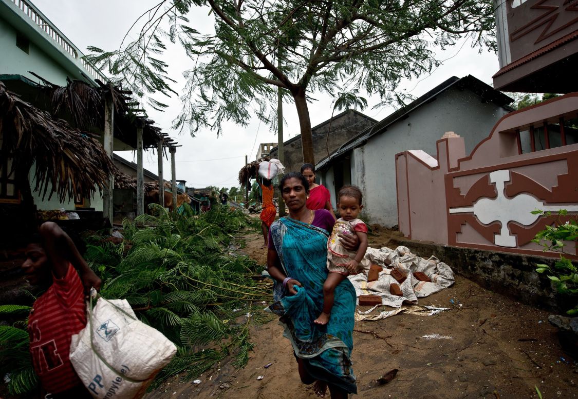 An Indian woman carries her child as they leave their home in Donkuru on October 12.