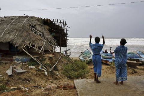 Indian women signal to fishermen to return following a cyclone alert before evacuating their village in Gokhurkuda on Friday, October 11.