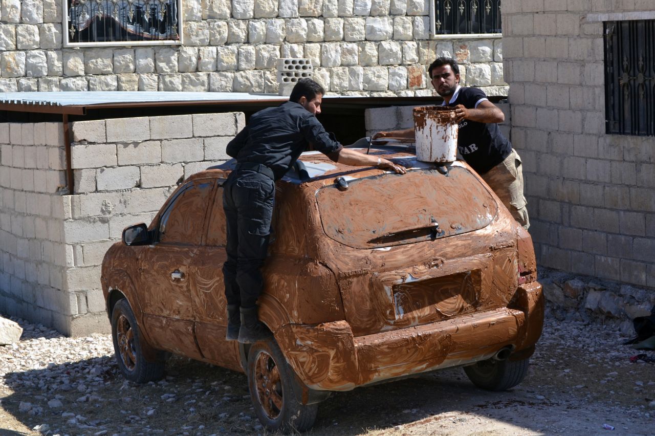 Rebel fighters cover a car in mud for camouflage at an undisclosed location in Syria's northwestern province of Idlib on Tuesday, October 8.