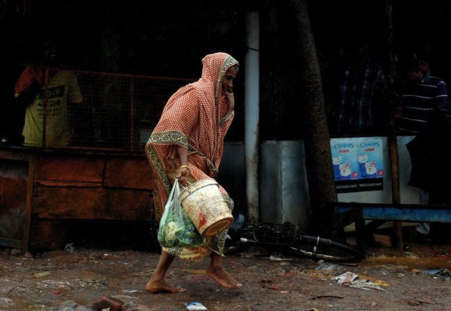 A woman carries daily essentials as she walks in a heavy wind in the town of Gopalpur on October 12.