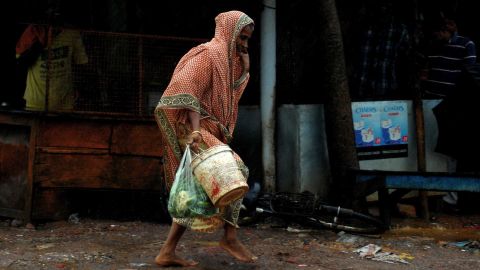 A woman carries daily essentials as she walks in a heavy wind in the town of Gopalpur on October 12.