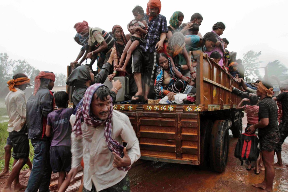 Evacuated villagers climb down from a truck at a relief camp near Berhampur on October 12