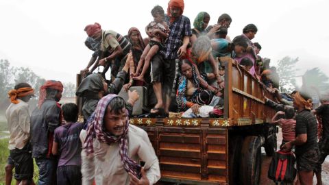 Evacuated villagers climb down from a truck at a relief camp near Berhampur on October 12
