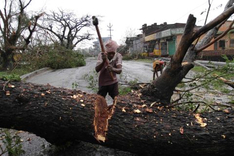 A municipal worker cuts a tree uprooted by the cyclone to clear a main highway in Berhampur, India, on October 13.