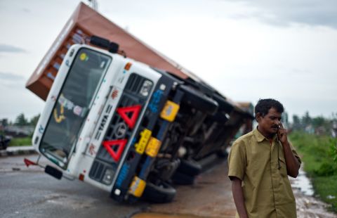 Indian truck driver Jairam Yadav speaks on his mobile phone after his truck carrying Toyotas was overturned by strong wind on the highway linking Andhra Pradesh and Odisha, India, on October 13.