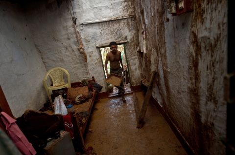 Janardan cleans his house of mud after overnight rains at the fishermen's colony in the town of Gopalpur on October 13.