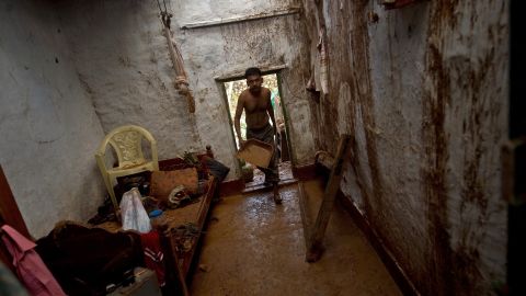 Janardan cleans his house of mud after overnight rains at the fishermen's colony in the town of Gopalpur on October 13.
