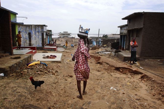 A villager carries drinking water in bottles as she arrives at the cyclone-hit village of Arjipalli on October 13.