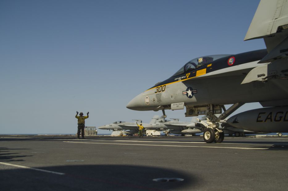 Landing Signal Officer guides in a fighter jet on the deck of the USS George Washington. The Naval Institute categorizes the Nimitz-class ship as a 'super carrier.' 
