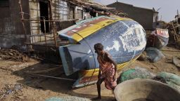 A woman walks near overturned boats in Pudumpeta, India, on Monday, October 14.