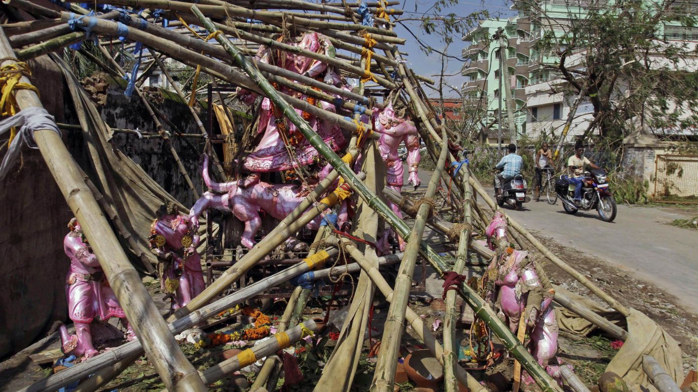 People drive past statues of Hindu gods and goddesses damaged during the storm in Berhampur, India, on October 14.