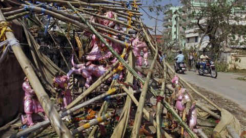 People drive past statues of Hindu gods and goddesses damaged during the storm in Berhampur, India, on October 14.